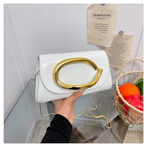 Close-up of white patent leather handbag featuring a large golden oval metal buckle and chain