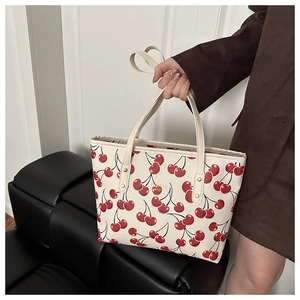 Detail of cherry print tote bag featuring FASHION BAGS text and reinforced metal rivets