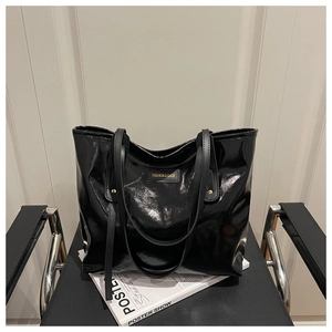 Detail of glossy black patent leather tote bag with Fashion & Bags logo on a chair