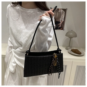 Detail of black woven shoulder bag with chic charms shown in a lifestyle interior