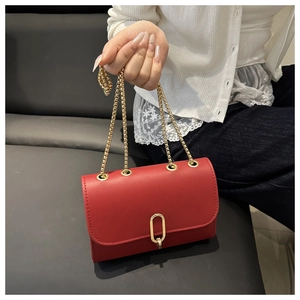 Détail du sac bandoulière en cuir rouge avec fermoir doré et fine chaîne élégante