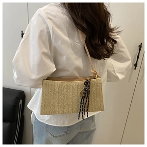 Detail of beige straw shoulder bag with V-shaped weave and decorative cord knot