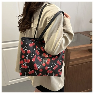 Vue lifestyle d'un sac cabas en cuir noir avec imprimé cerise porté par un mannequin
