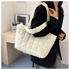 Close-up of white quilted tote bag with soft padded straps on a stylish model