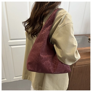 Detail of burgundy leopard print hobo tote bag featuring a glossy texture and wide strap