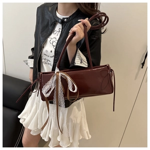 Detail of burgundy patent leather handbag featuring elegant lace bow and silk ribbons