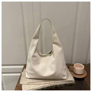 Close-up of cream minimalist tote bag on wooden table with elegant lifestyle props
