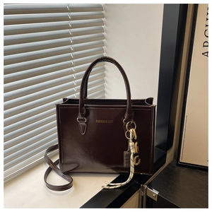 Detail of coffee brown tote with glossy finish, gold lettering and creative charms