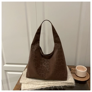 Close-up of brown leopard print hobo bag in suede texture resting on a cozy scarf