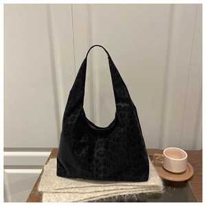 Detail of black leopard print hobo tote bag on a wooden table with soft natural lighting