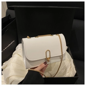 Détail d'un petit sac carré en cuir blanc avec bandoulière dorée dans un coffret cadeau de luxe