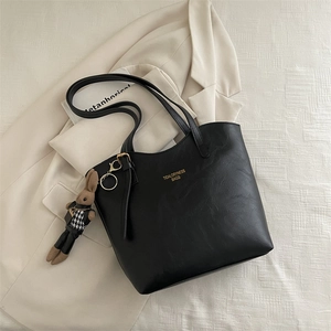 Minimalist black leather tote bag with a cute bunny charm and golden brand text logo
