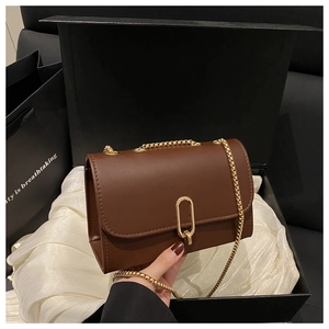 Détail du sac en cuir marron avec boucle dorée et chaîne dans un coffret cadeau