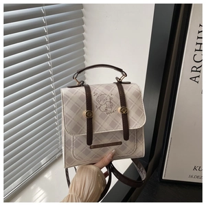 Detail of plaid bag with brown leather handles and cute cartoon dog print pattern