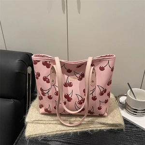 Pink cherry print tote bag with gold lettering shown on a stylish lifestyle background