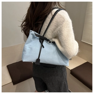 Vista posteriore della modella con borsa tote in tela azzurra e spalline in pelle