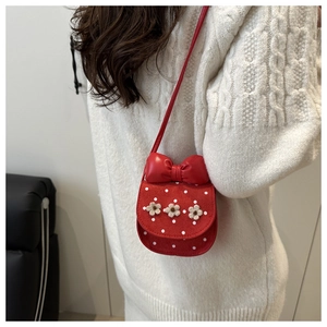 Détail du sac bandoulière rouge avec gros nœud et fleurs 3D porté par un mannequin