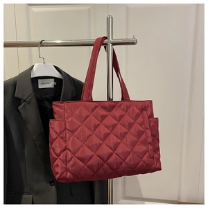 Detailed view of red quilted tote bag with diamond stitching and side pocket storage