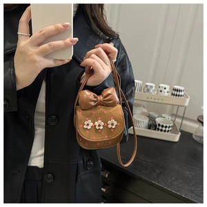 Détail du mini sac bandoulière avec nœud en cuir, pois et petites fleurs blanches