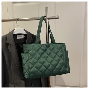 Detailed dark green quilted tote bag with diamond stitching on a metal hanger