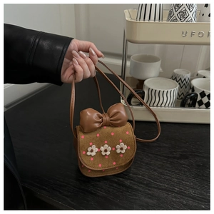Détail du mini sac bandoulière marron avec nœud en cuir, pois roses et fleurs