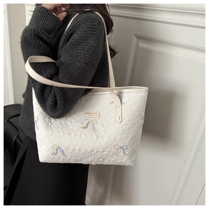 Close-up of white tote bag with embossed pattern and colorful bow details on a model