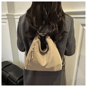Gros plan du sac hobo en daim beige mat avec fermeture éclair verticale sur une épaule