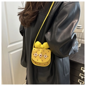 Détail du sac bandoulière jaune avec grand nœud, pois marron et touches florales en 3D