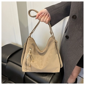Gros plan d'un sac cabas kaki en faux daim avec fermeture éclair verticale et longs glands