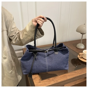 Dettaglio della borsa tote in denim blu con manici neri e fibbia metallica