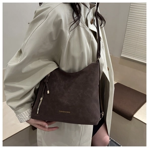 Détail du sac hobo en cuir mat marron foncé avec texte doré et accents de fermeture