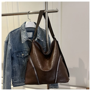 Détail du sac hobo en cuir ciré marron foncé avec fermetures éclair argentées et sangle