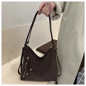 Détail du sac cabas en daim moka mat avec fermeture éclair métallique et logo imprimé