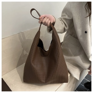 Gros plan sur la texture en cuir tressé et l'anse marron d'un grand sac cabas chic
