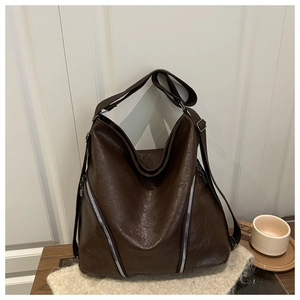 Détail d'un sac hobo marron foncé montrant la texture plissée et les fermetures éclair argentées
