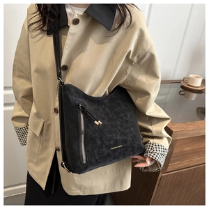Détail du grand sac Hobo en daim noir avec fermeture éclair argentée et lettrage doré