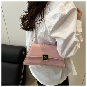 Close-up of light pink leather bag with gold M-logo buckle on model with white shirt
