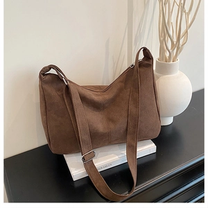 Detail of deep brown suede hobo bag with adjustable strap and silver metal buckle