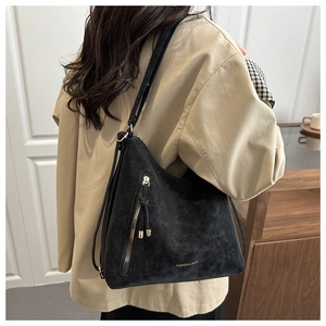 Détail du sac hobo en daim noir avec fermetures éclair diagonales et finitions dorées