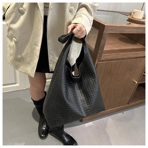 Vue détaillée de la texture tressée noire et du cuir sur un grand sac cabas