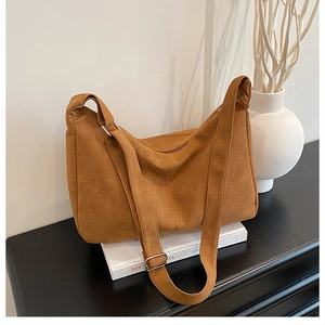 Detailed close-up of brown suede hobo bag with silver buckle in a minimalist setting