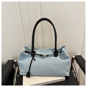 Detail of light blue denim tote with black leather straps and metal buckle fastener