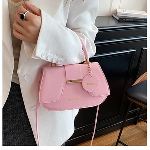 Detail of pink saddle bag with gold chain strap and fashion logo on white blazer