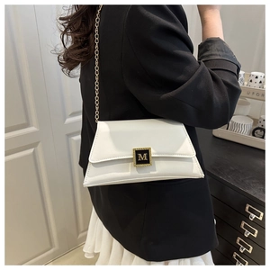 Detailed view of white leather trapezoid bag featuring gold letter M buckle and chain strap