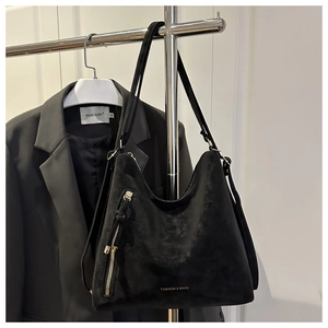 Détail du sac hobo en daim noir avec lettrage doré et fermeture éclair métallique