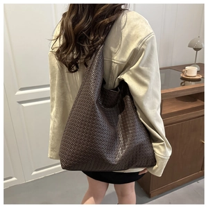 Modèle portant un grand sac cabas tressé marron foncé pour la mode d'automne et les loisirs