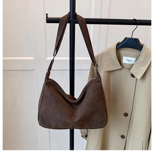 Detail view of deep brown suede hobo bag with adjustable strap on a garment rack