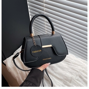 Close-up of black matte PU leather saddle bag with gold hardware and fashion pendant