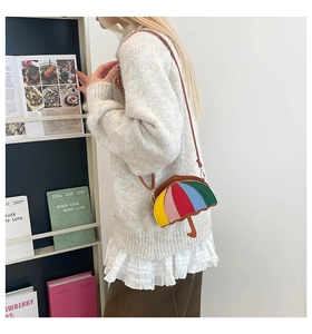 Detail of creative rainbow umbrella-shaped crossbody bag on white oversized sweater