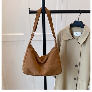 Close-up of a retro brown suede crescent bag hanging on a rack for autumn and winter fashion